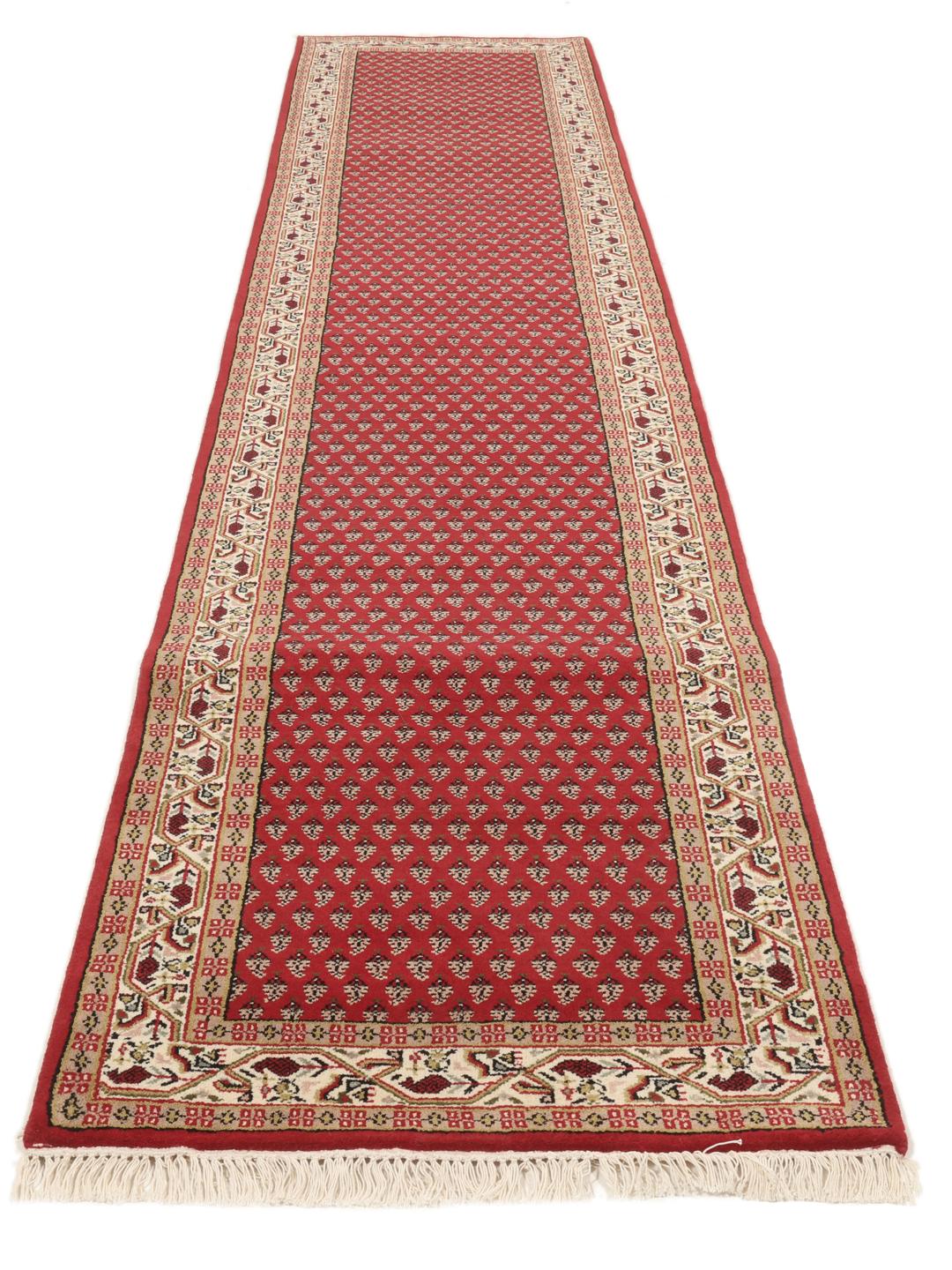 Un long tapis de couloir Mir Indo noué à la main, originaire d'Inde, avec un champ rouge profond et un motif floral complexe.