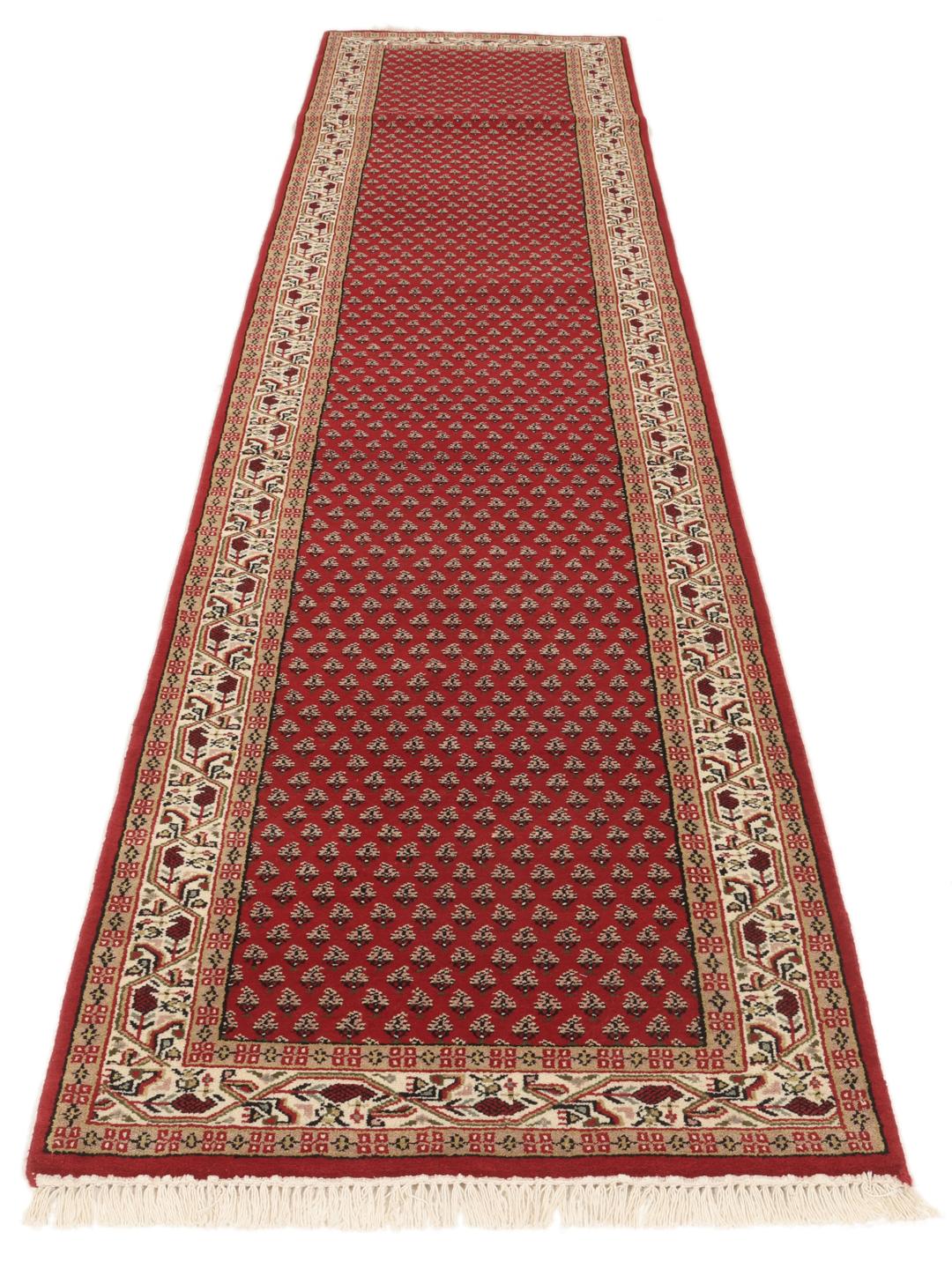 Un long tapis de couloir Mir Indo noué à la main, originaire d'Inde, avec un champ rouge profond et un motif floral complexe.