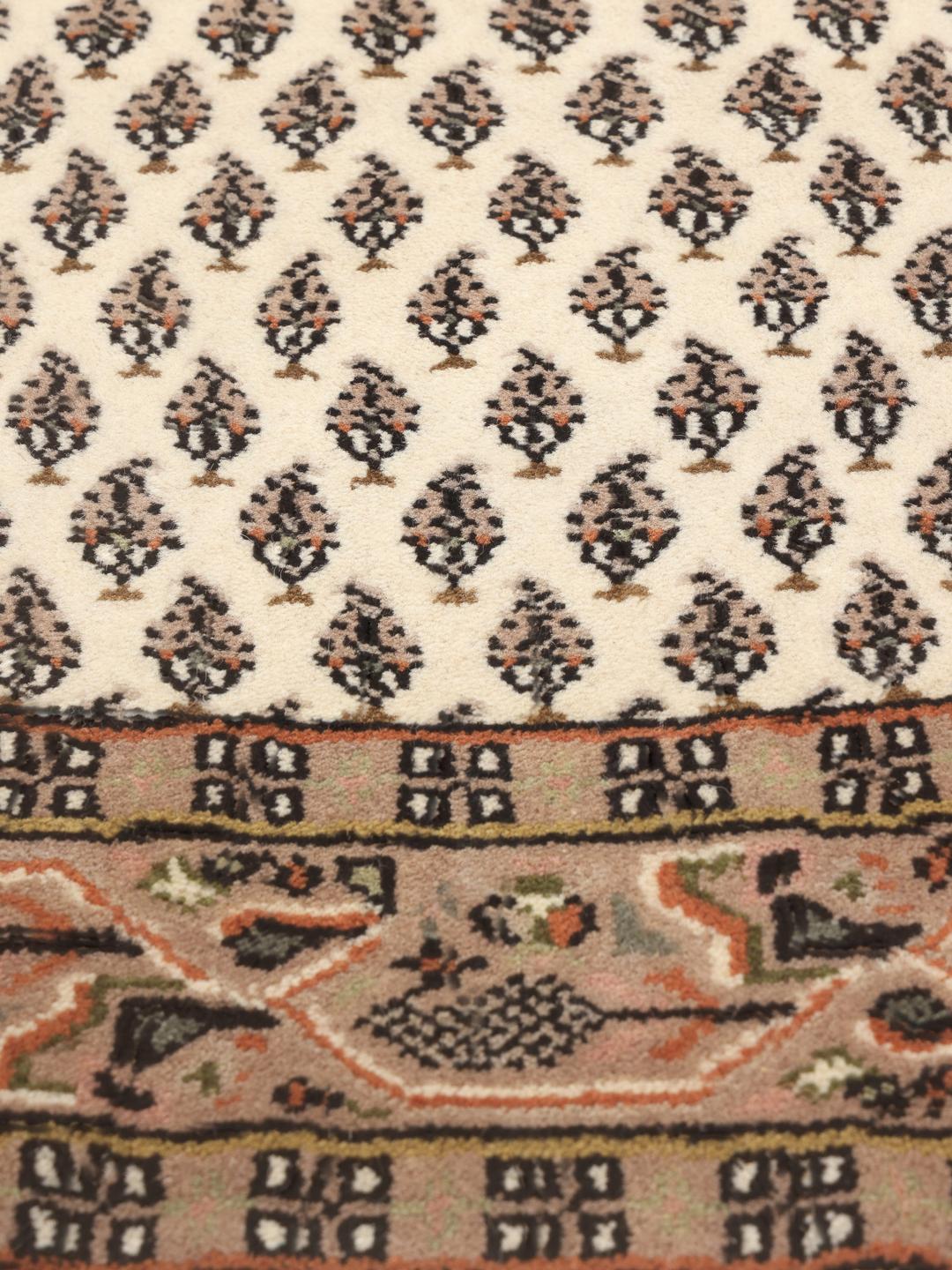 Tapis Mir Indo noué à la main originaire d'Inde avec un fond beige et des motifs floraux répétitifs.