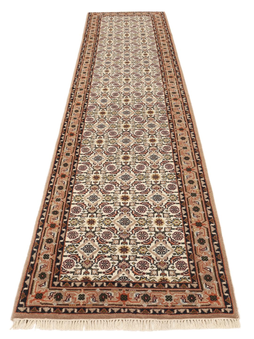 Un tapis de couloir beige noué à la main en provenance d'Inde avec un motif traditionnel.