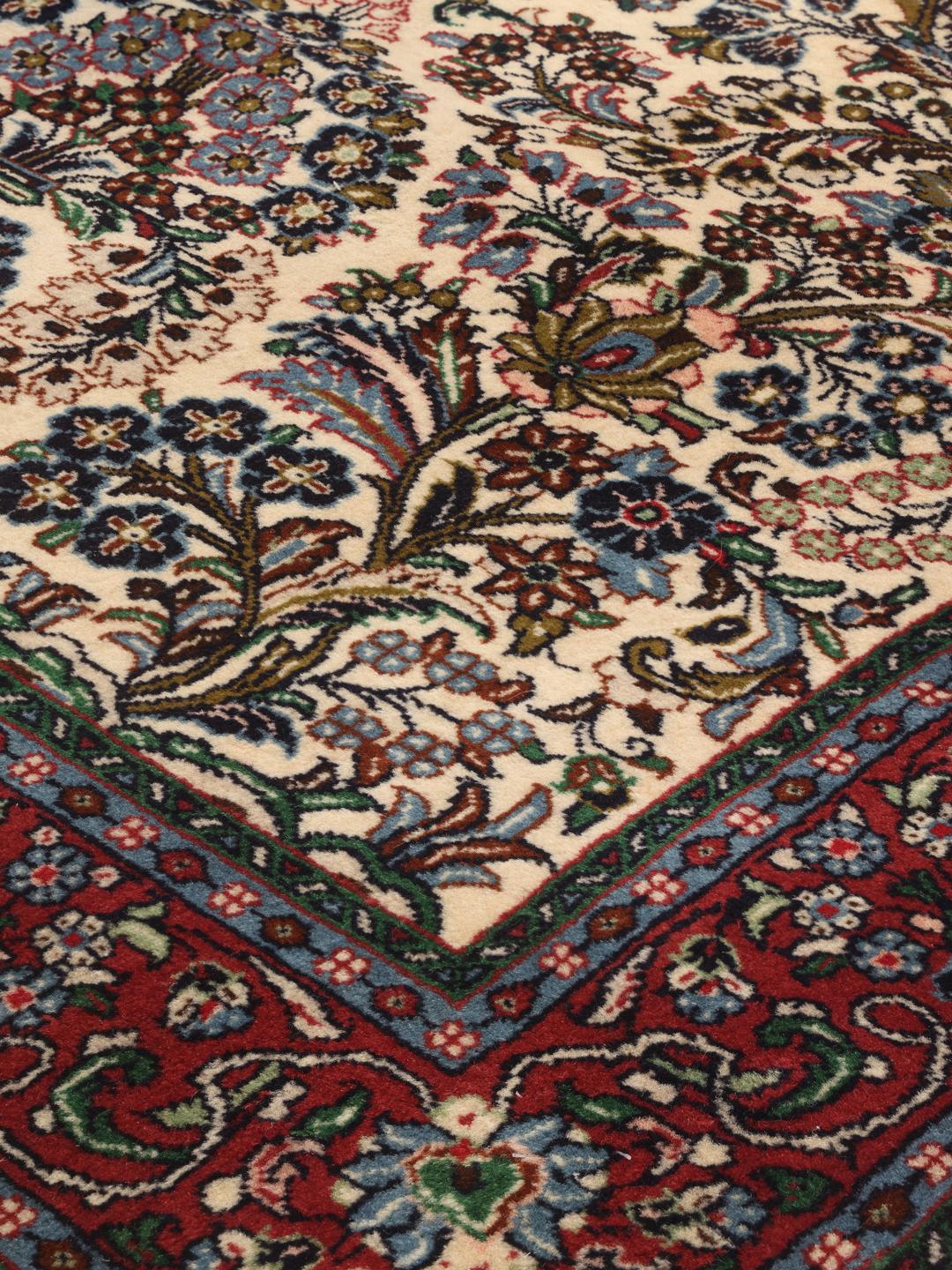 Hand-knotted Sarough rug with a floral vase pattern in red and beige tones.