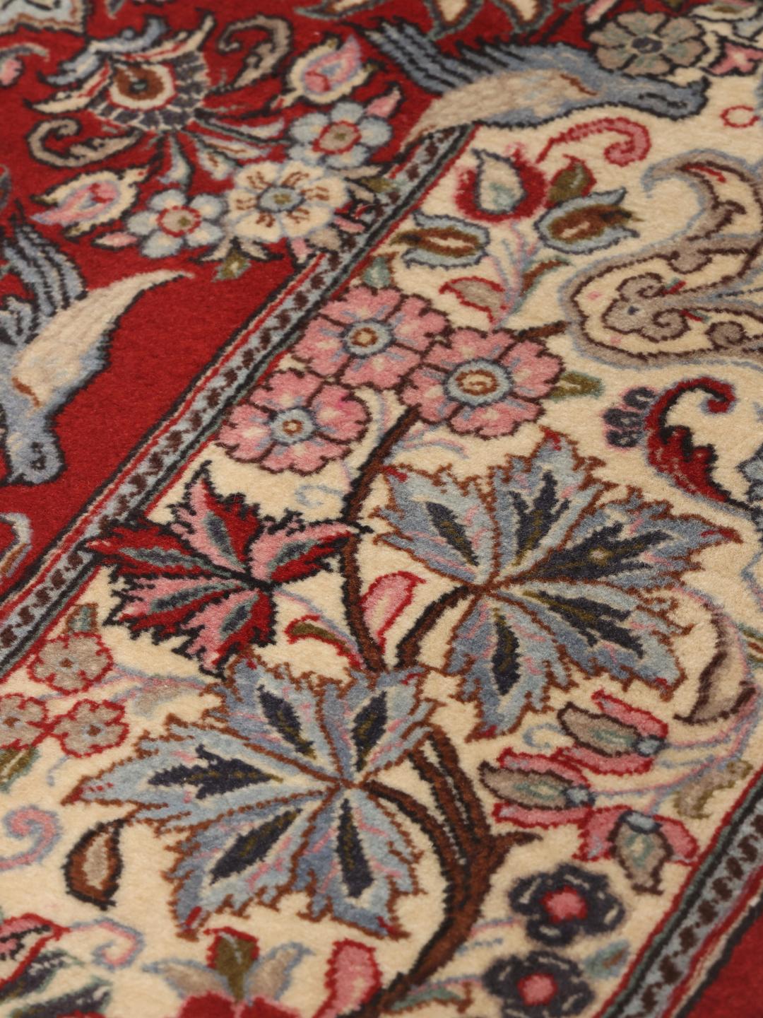 A hand-knotted Sarough rug from the Middle East featuring a red field with floral patterns.