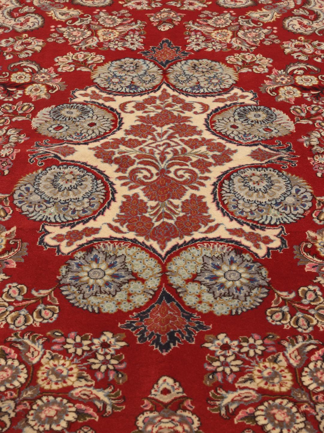 A hand-knotted red Sarough rug with intricate floral patterns.