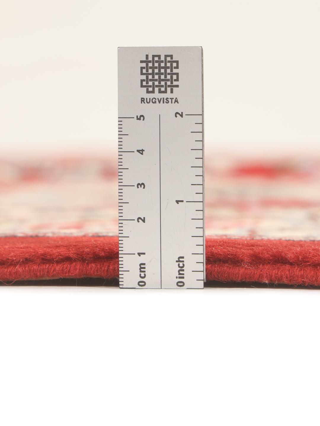 A hand-knotted red Sarough rug with intricate floral patterns.