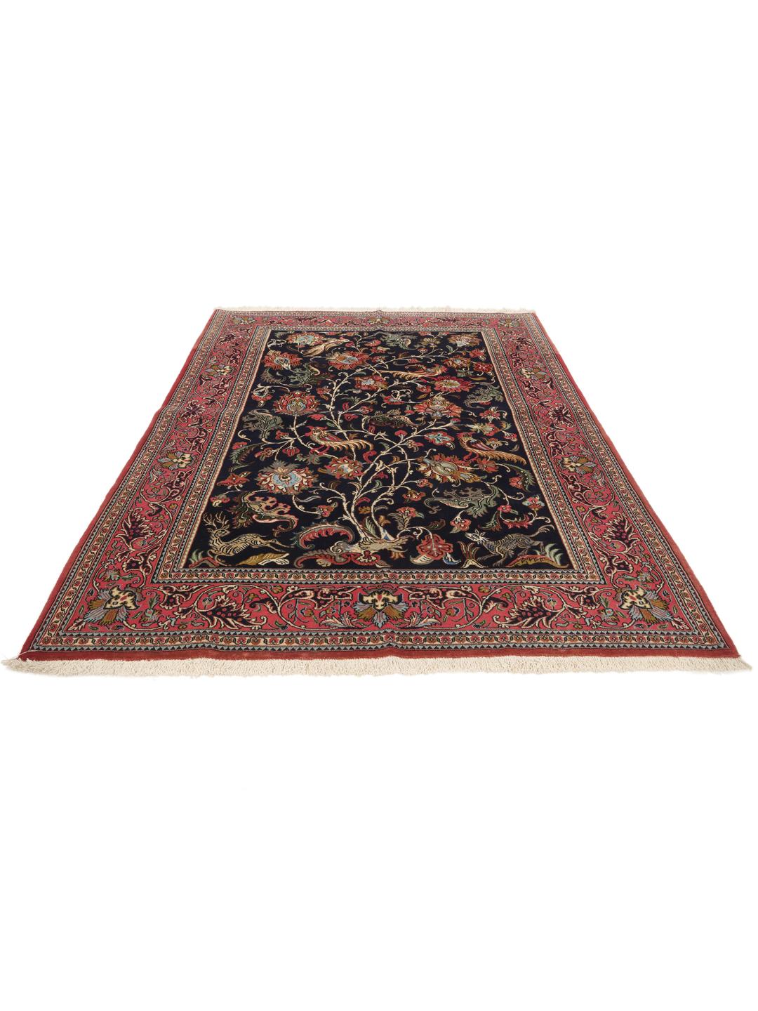 A hand-knotted Sarouk rug from the Middle East featuring a dark-blue field with colourful floral motifs