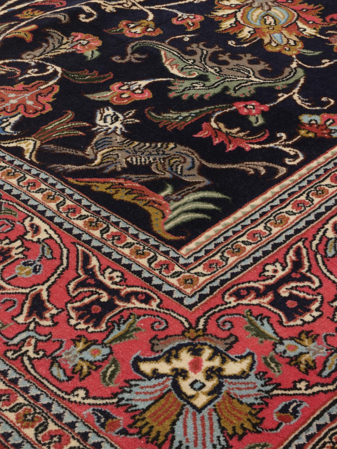 A hand-knotted Sarouk rug from the Middle East featuring a dark-blue field with colourful floral motifs