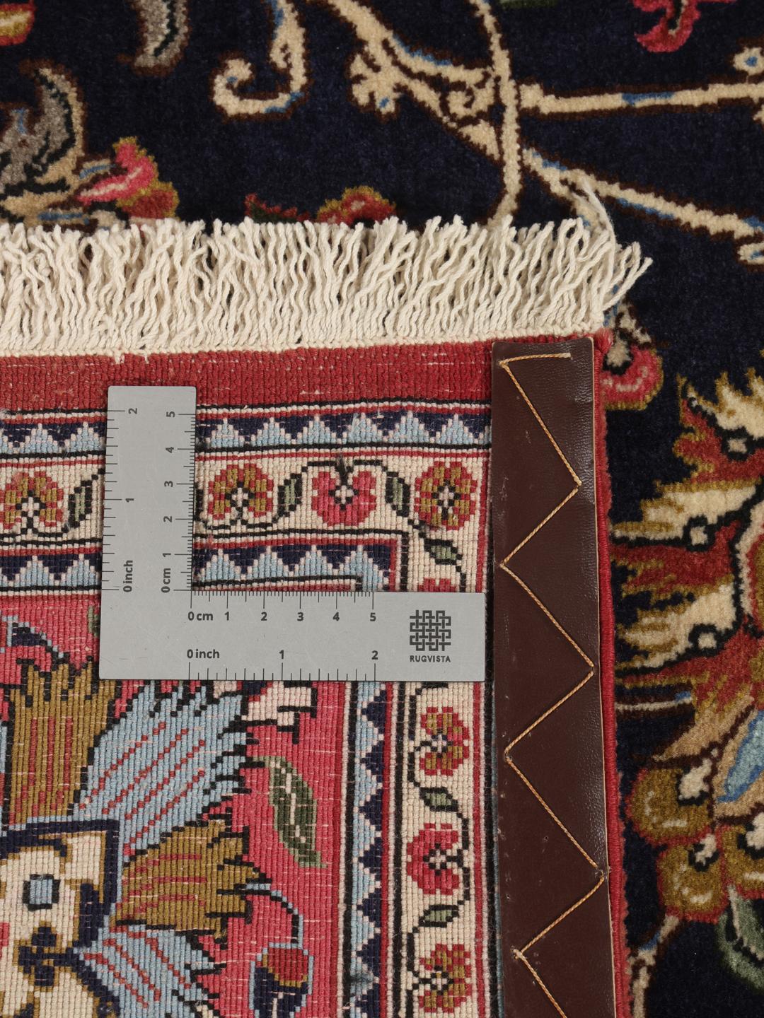 A hand-knotted Sarouk rug from the Middle East featuring a dark-blue field with colourful floral motifs