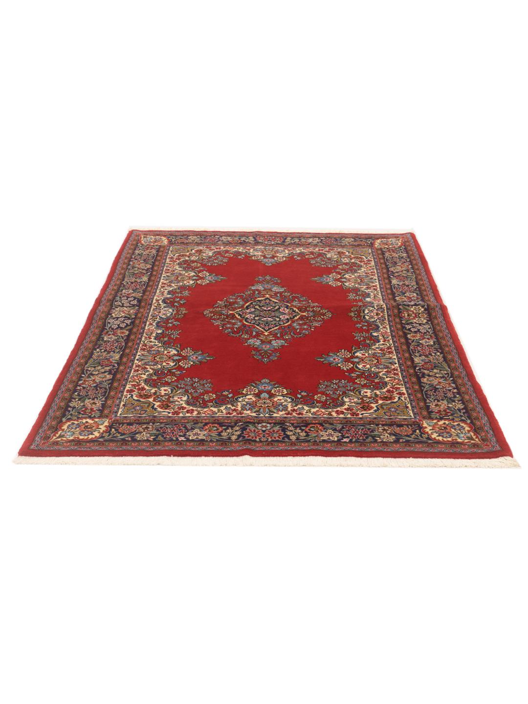 A hand-knotted Sarough rug from the Middle East with a red field and floral motifs.