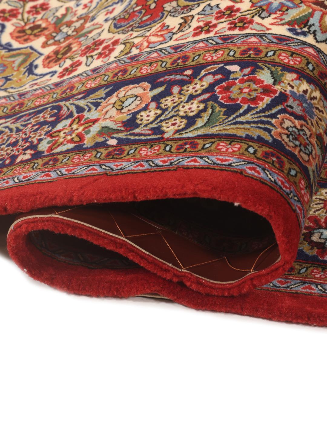 A hand-knotted Sarough rug from the Middle East with a red field and floral motifs.