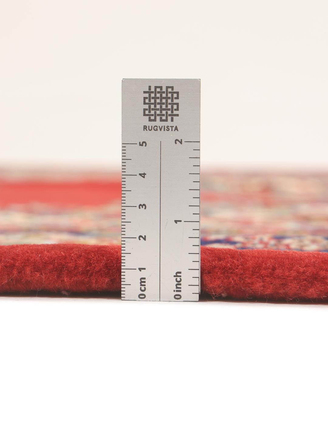 A hand-knotted Sarough rug from the Middle East with a red field and floral motifs.