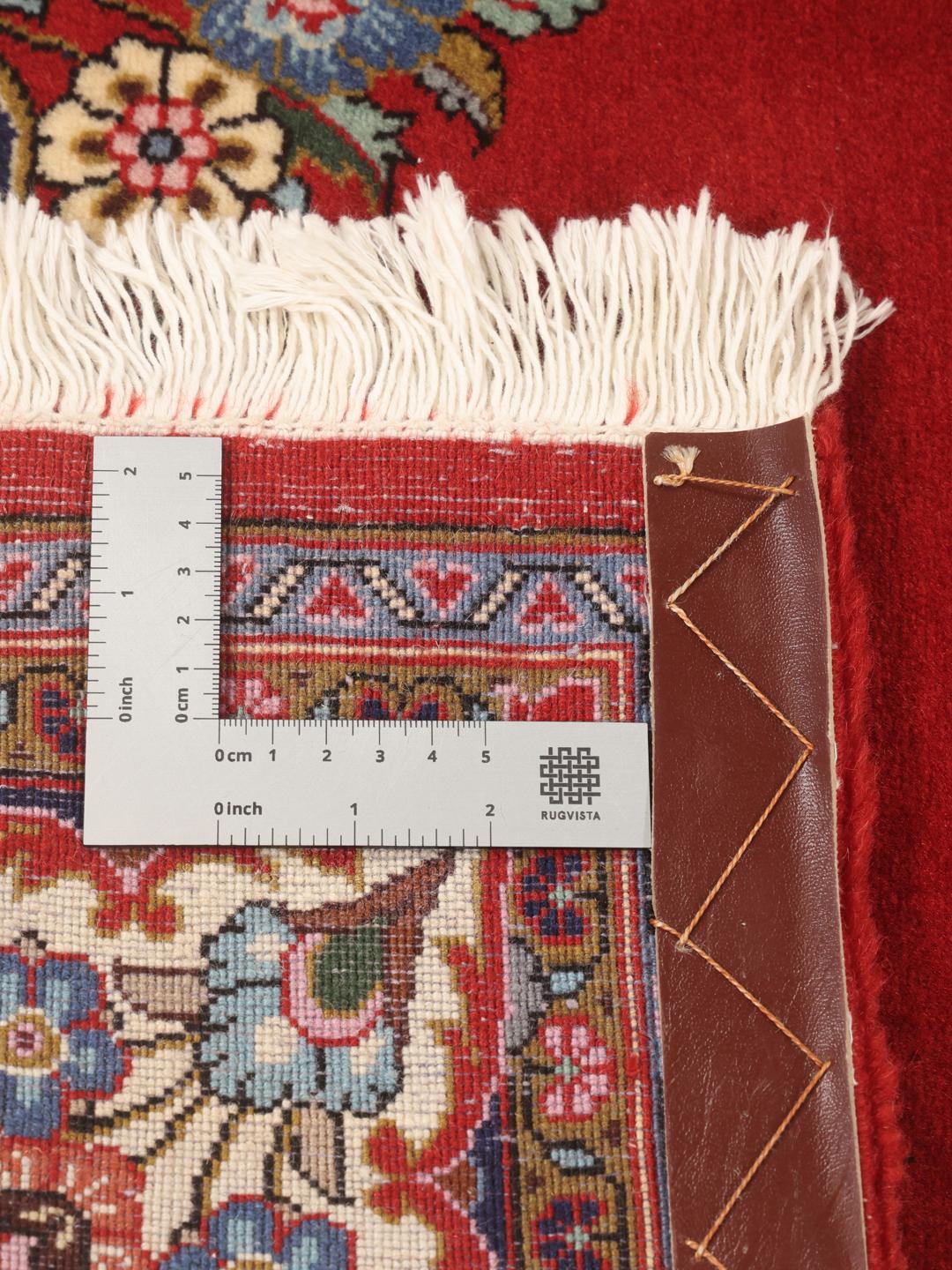 A hand-knotted Sarough rug from the Middle East with a red field and floral motifs.