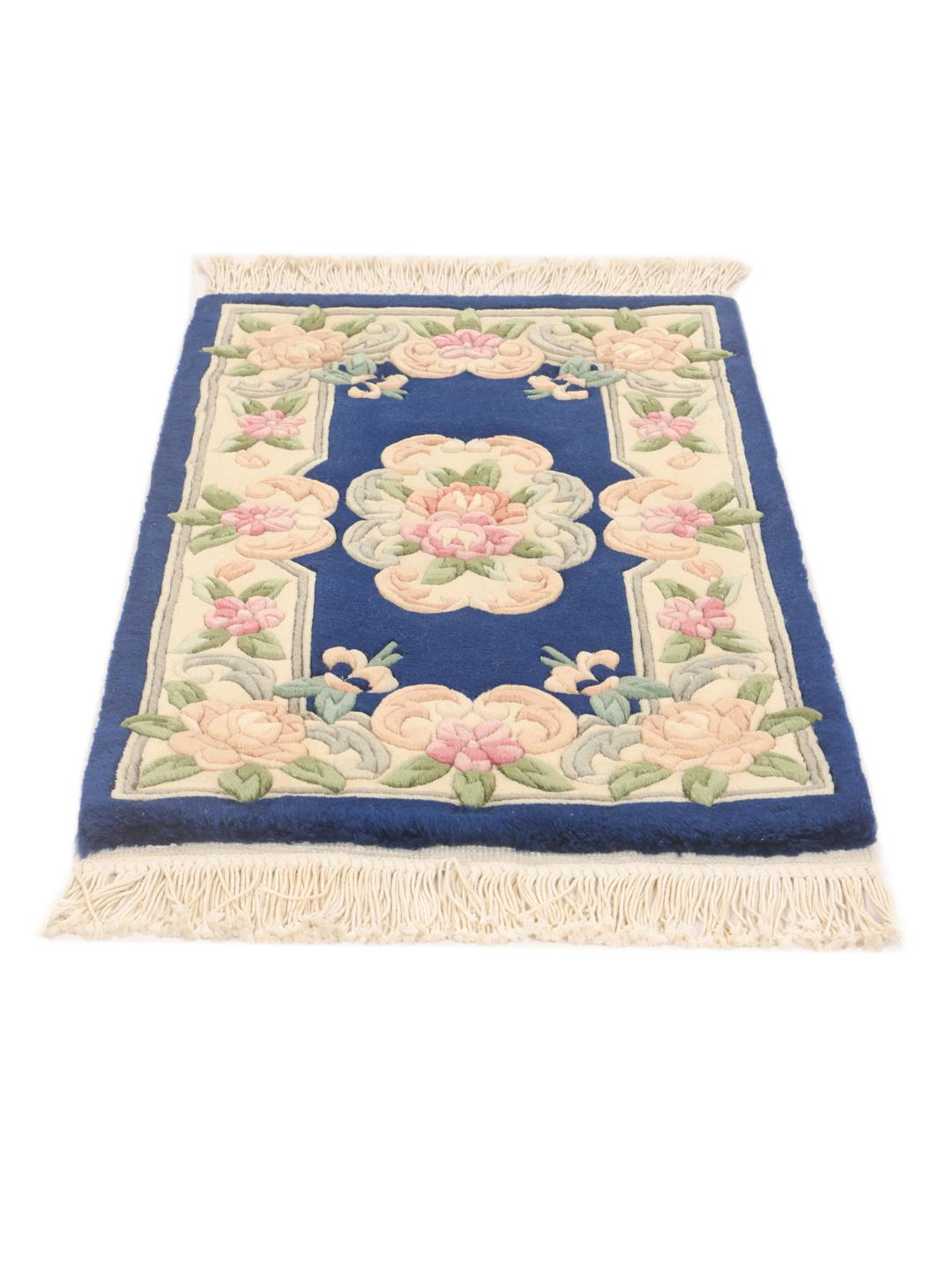 A rectangular hand-knotted rug from China featuring a deep blue field with floral motifs.