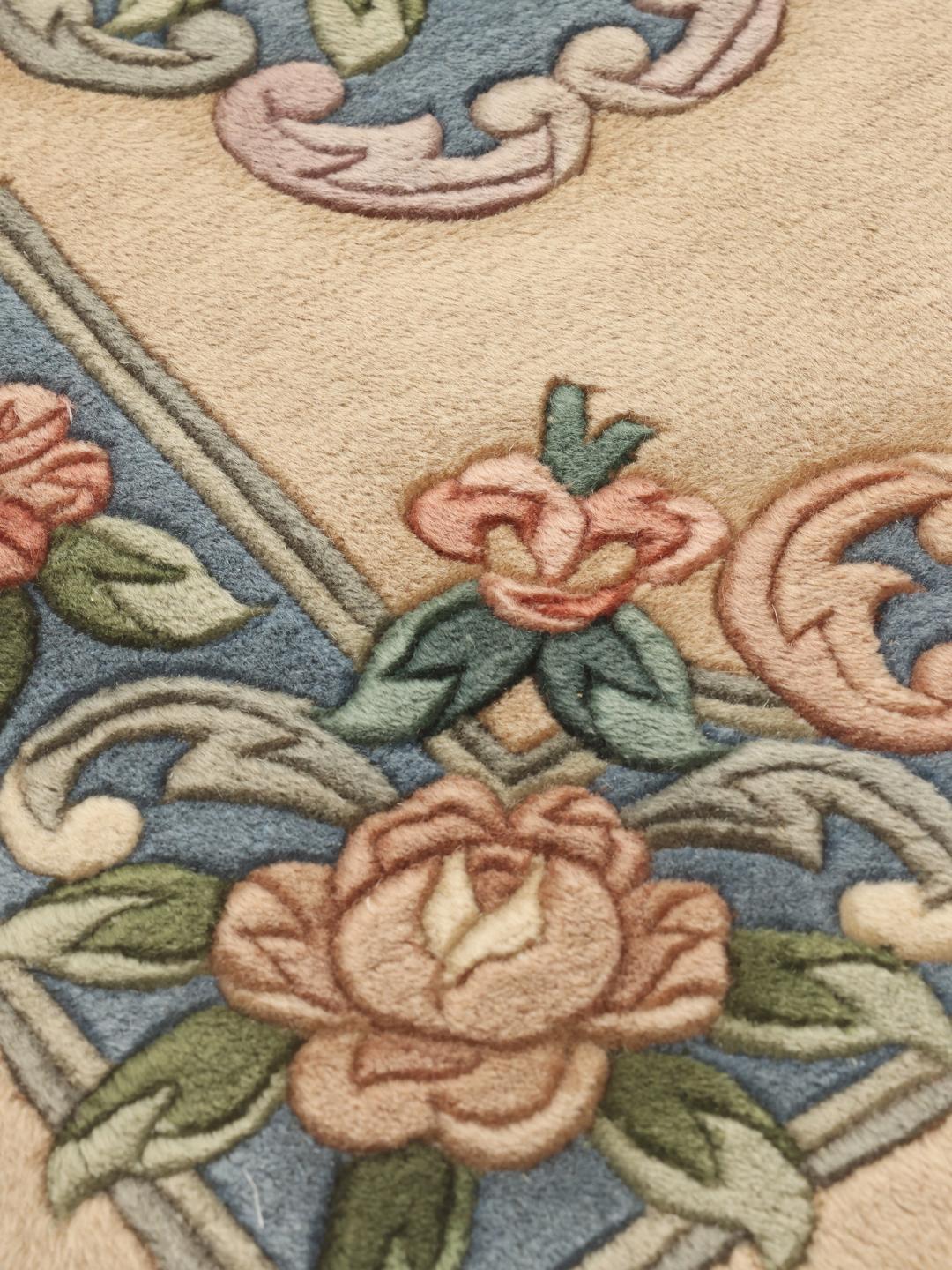Et rektangulært håndlavet kinesisk tæppe med et blomstermønster i beige, blå, lyserød og grøn.