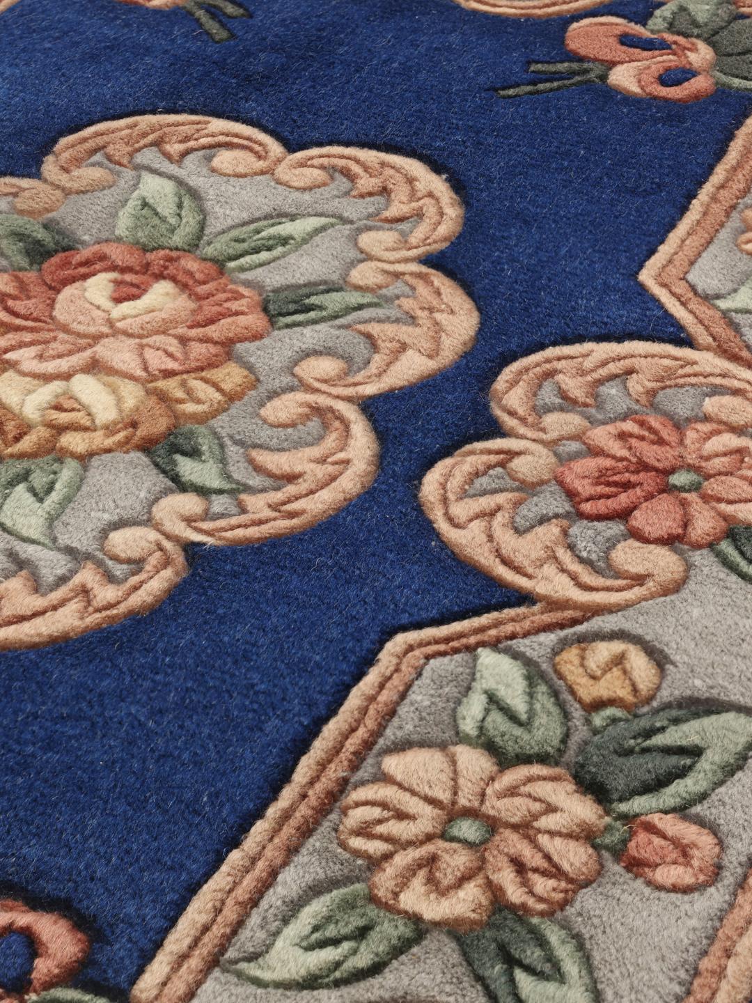 Et rektangulært, håndknyttet kinesisk tæppe med en dyb blå bund og blomstermotiver.