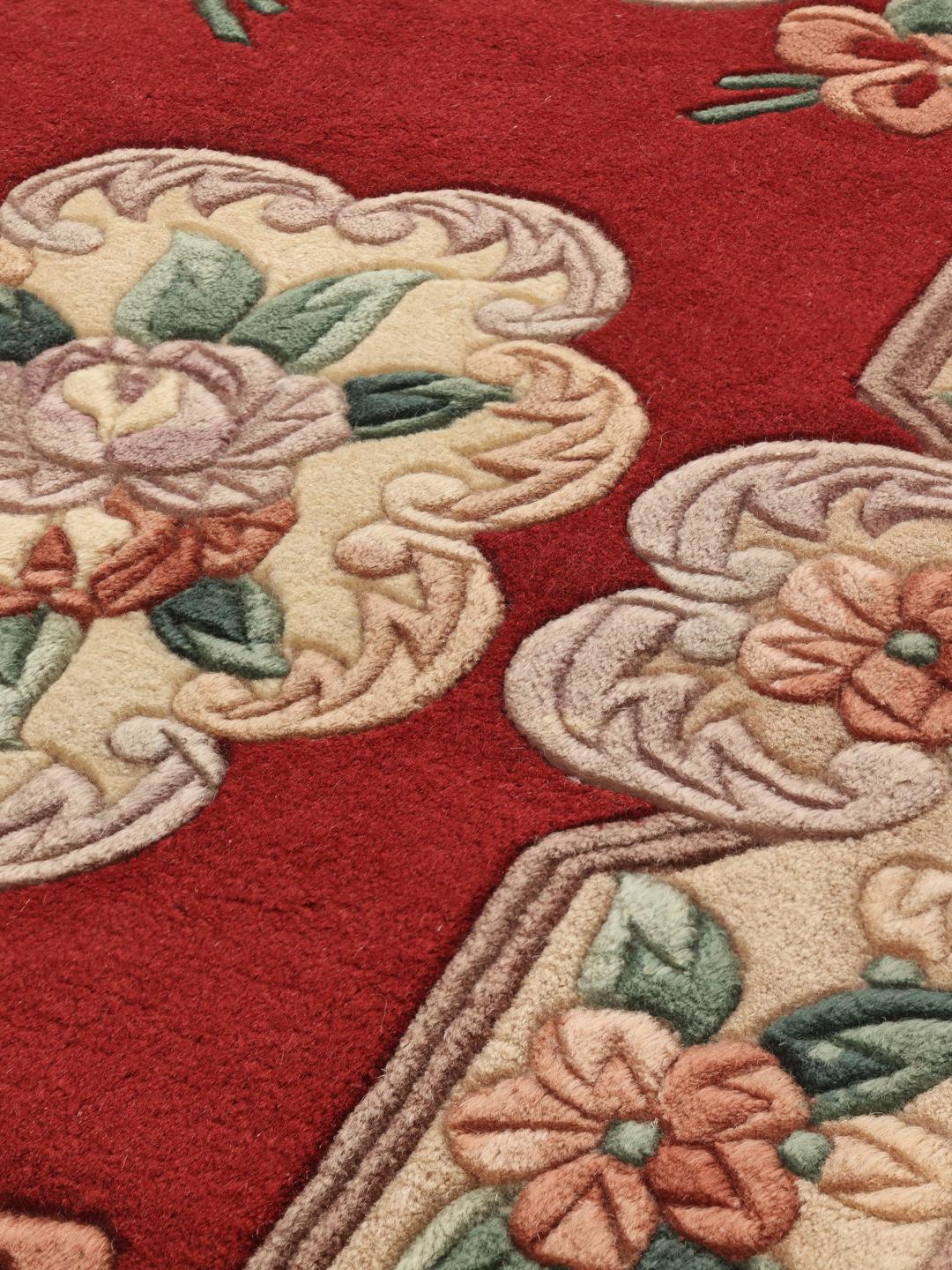 Et rektangulært kinesisk tæppe med en rød bund og et detaljeret blomstermotiv