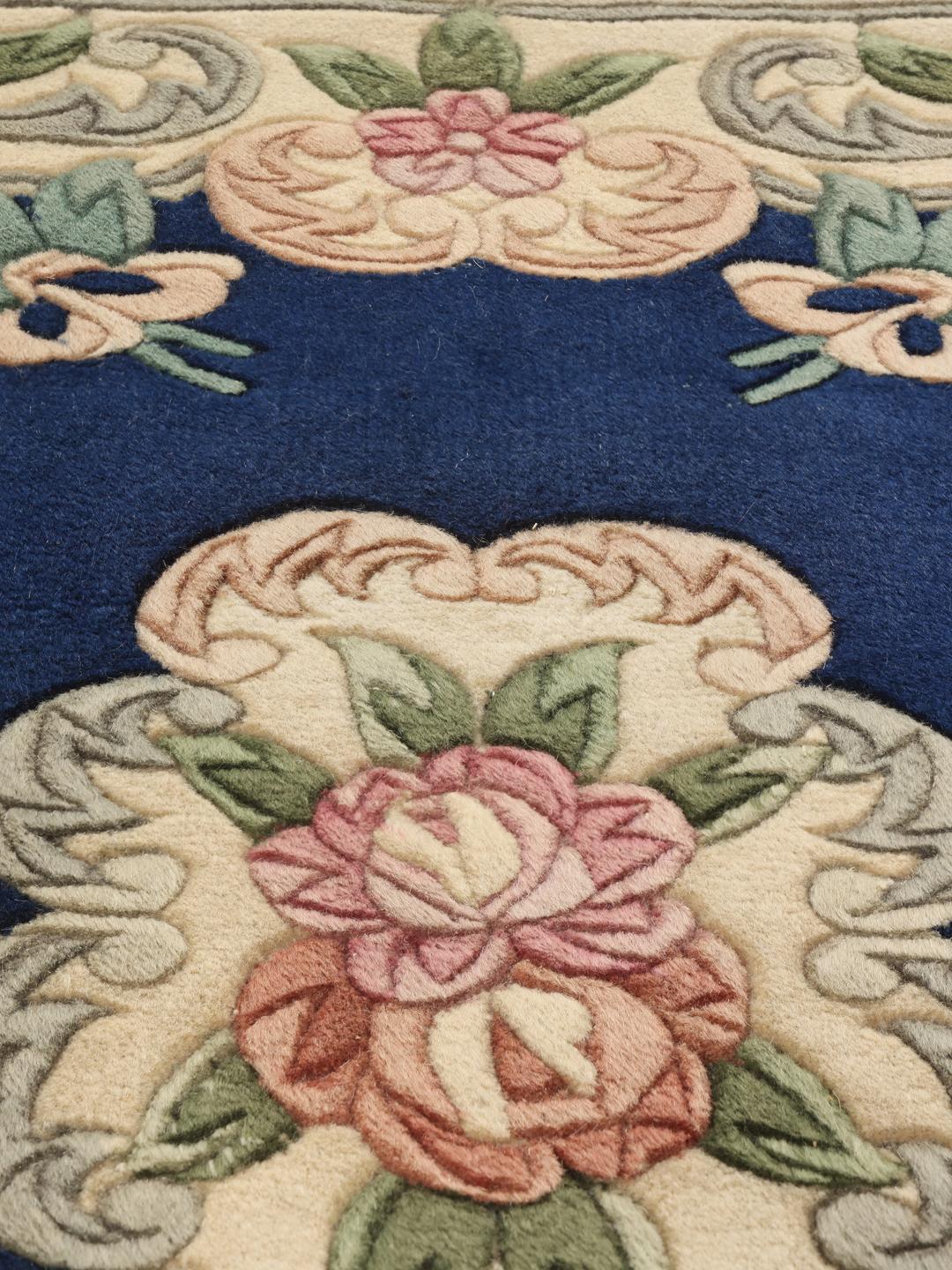 Håndknyttet blomstret tæppe fra Kina med blå bund og pastelfarvede blomster.