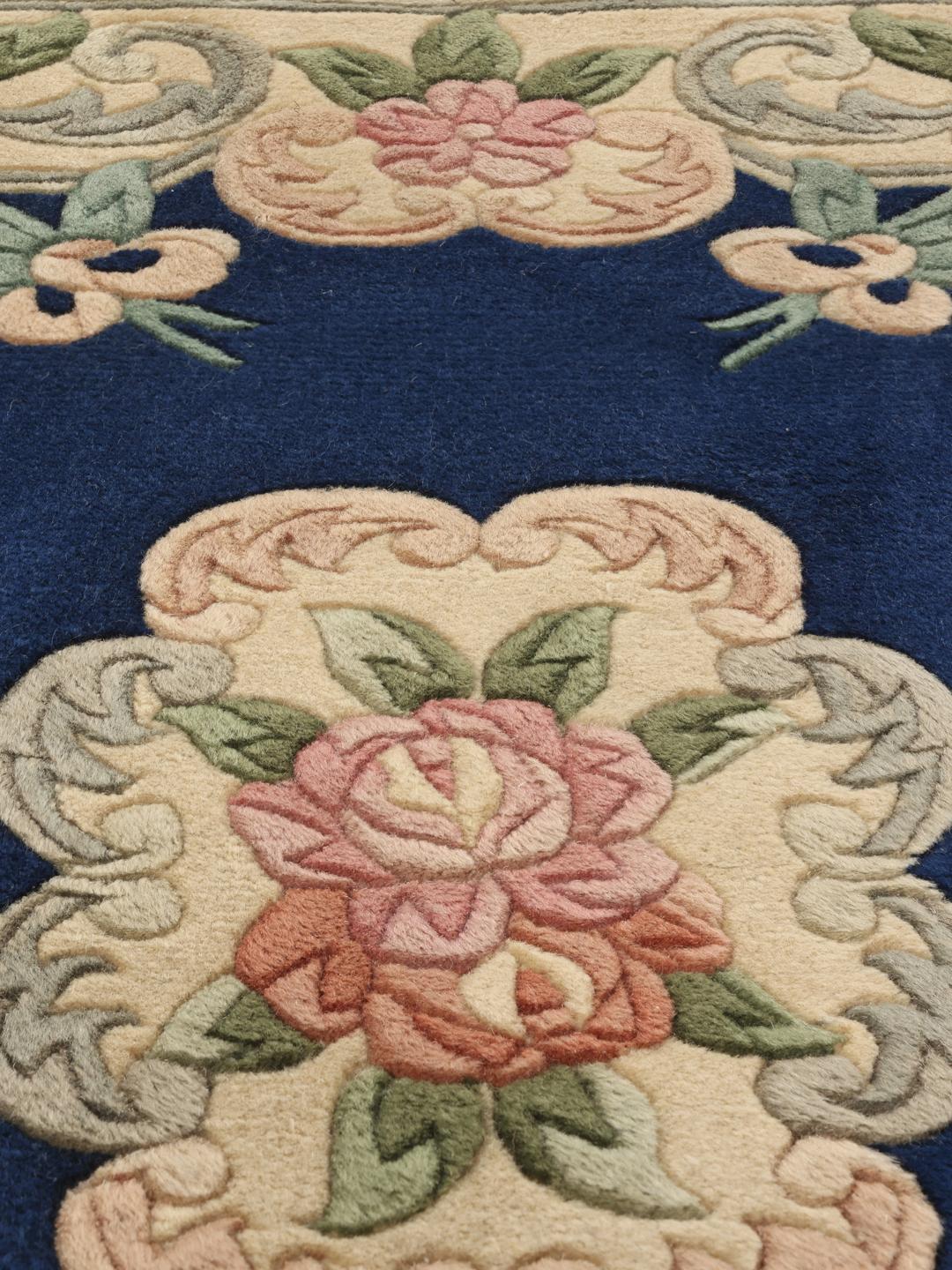 Håndknyttet blomstret tæppe fra Kina med en dybblå baggrund og bløde pastelblomster.