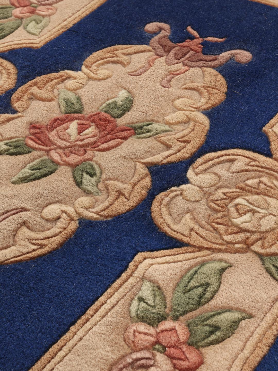 Et håndknyttet blomstret kinesisk tæppe i blå og beige toner.