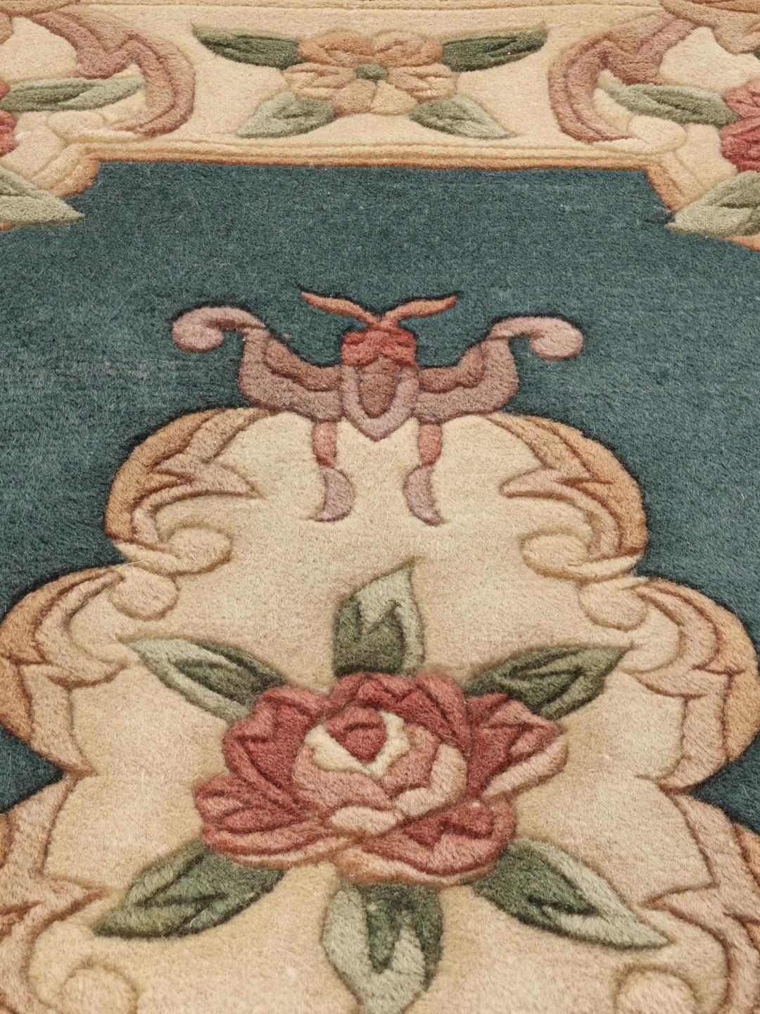 Et håndknyttet kinesisk tæppe med blomstermotiver i teal og beige.