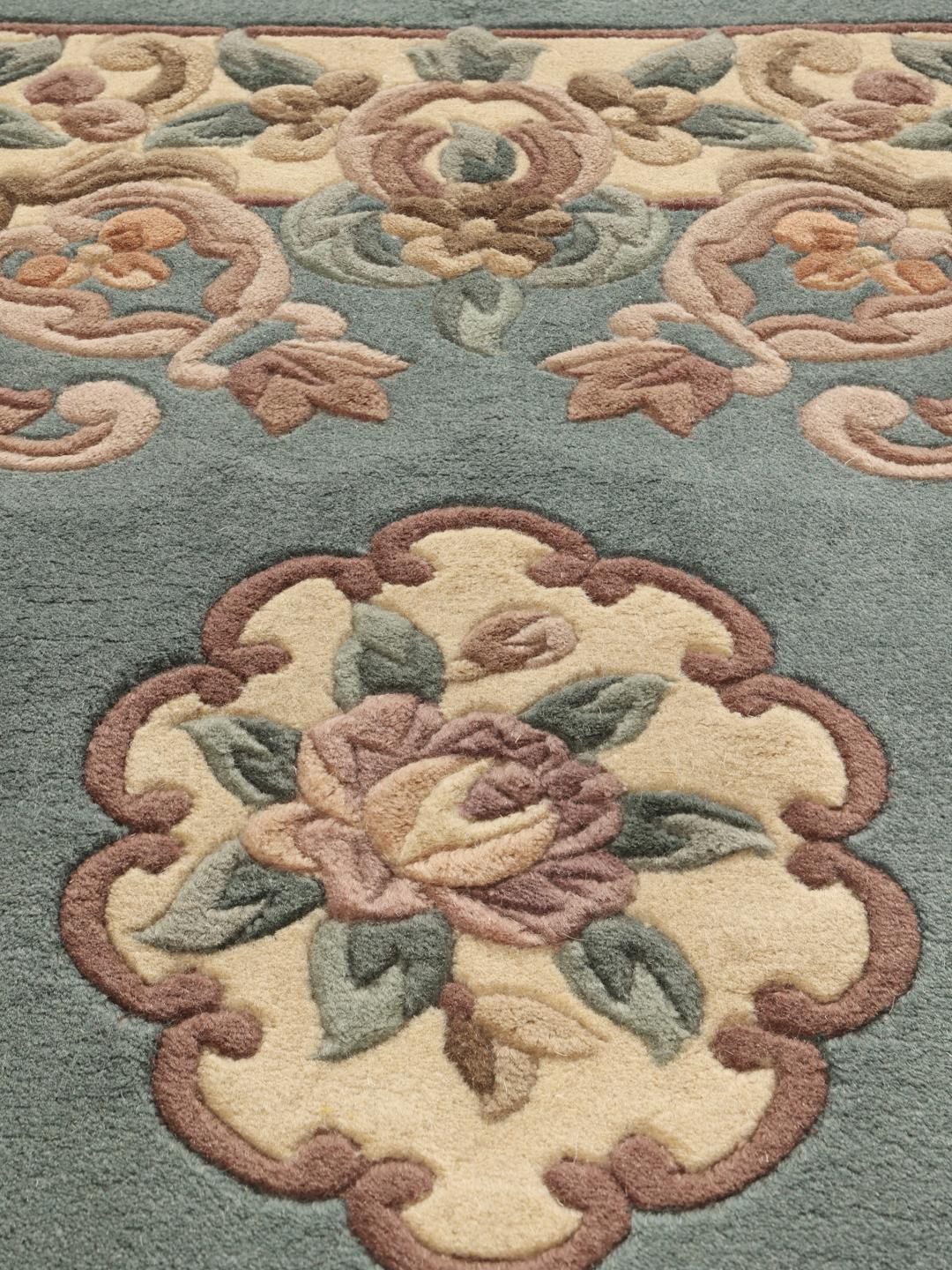 Håndknyttet kinesisk tæppe med blomstermotiver i lyseblå og beige.