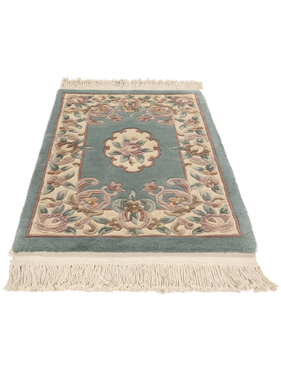 Et rektangulært håndknyttet tæppe fra Kina med et blomstermønster i lyseblå og beige.
