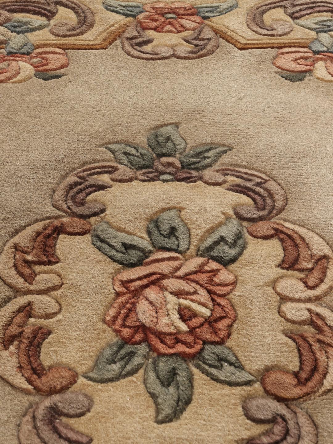 Et rektangulært kinesisk tæppe med blomstermotiver på en beige baggrund.