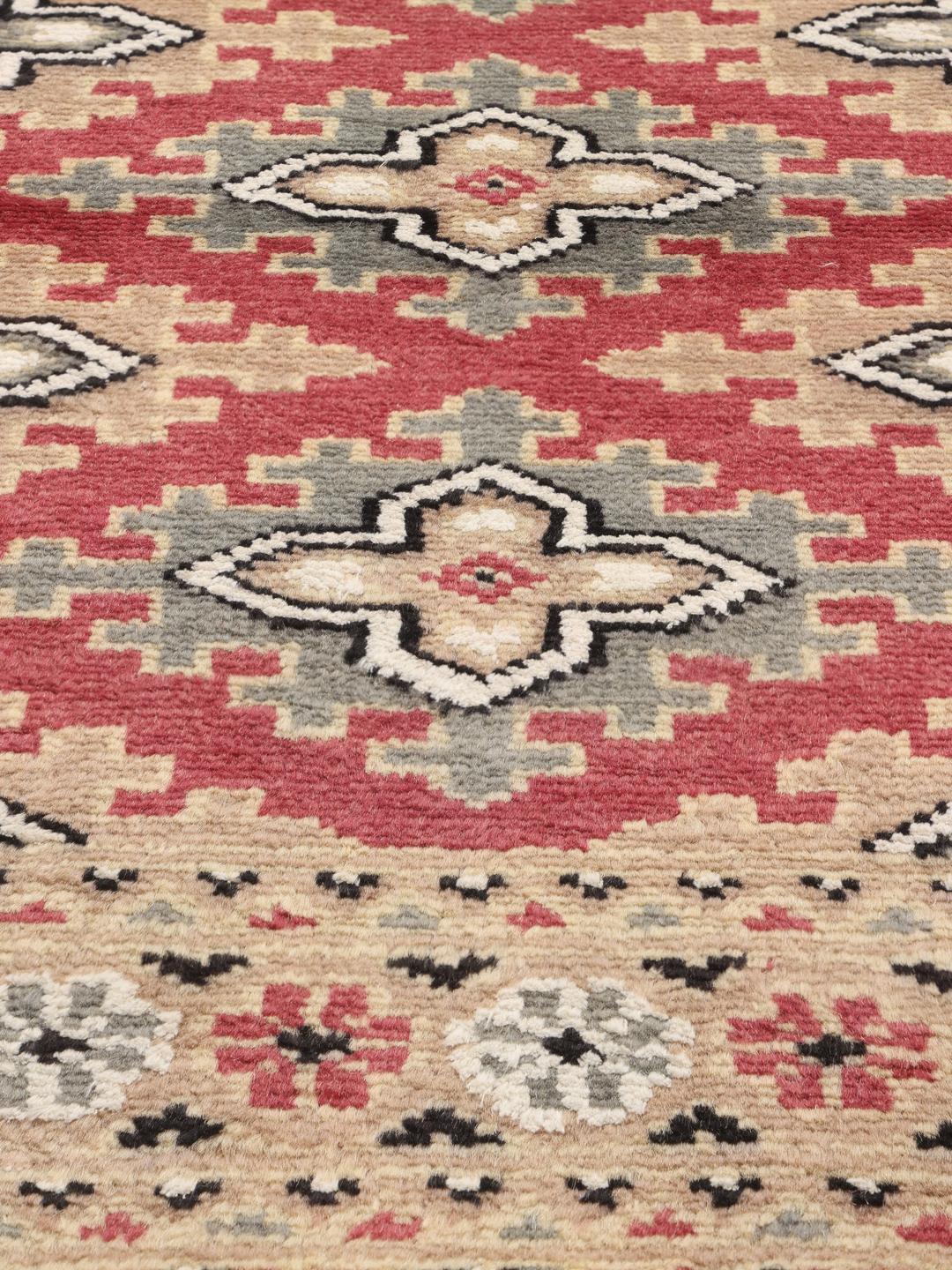 Hand-knotted Pakistan Bokhara rug featuring red and beige geometric patterns.