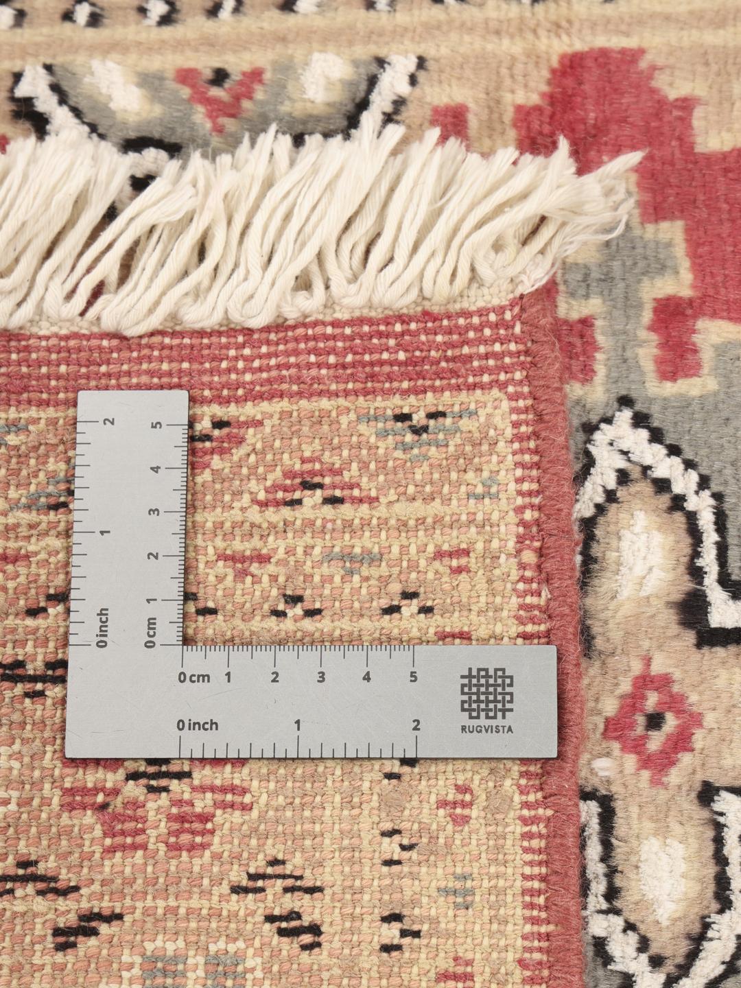 Hand-knotted Pakistan Bokhara rug featuring red and beige geometric patterns.