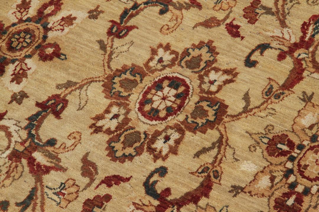 Een handgeknoopt tapijt uit India met een beige achtergrond en klassieke bloemmotieven.