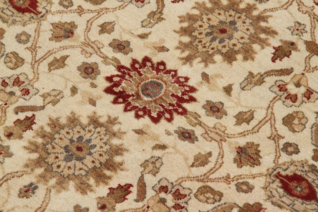 Handgeknoopt Indiaas kleed met een klassiek bloemmotief in beige en rode tinten.