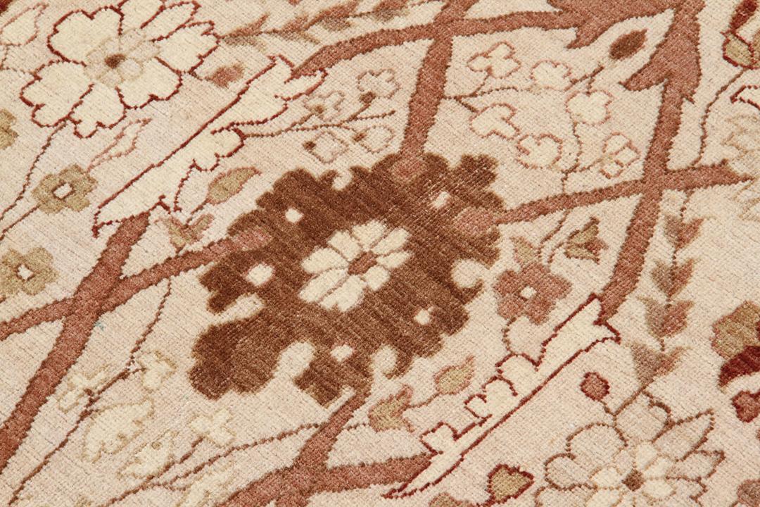 Handgeknoopt Indiaas tapijt met bloemmotieven in beige en rode tinten.