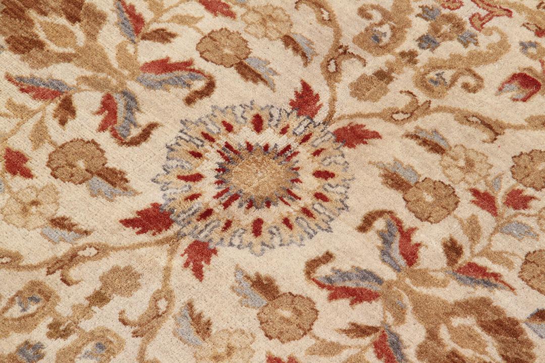 Een handgeknoopt Indiaas tapijt met een bloemmotief in beige en rood.