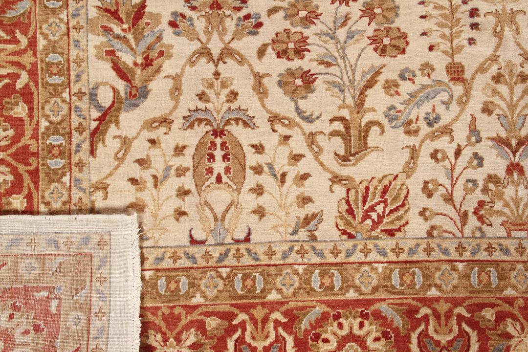 Een handgeknoopt Indiaas tapijt met een bloemmotief in beige en rood.