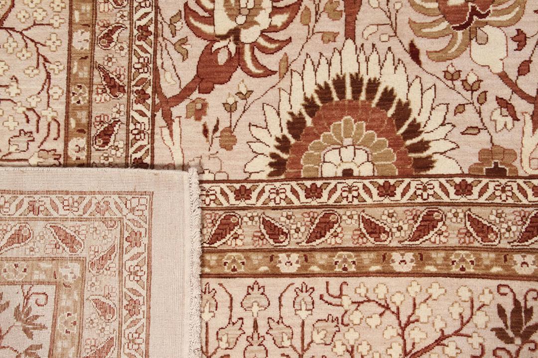 Et stort rektangulært håndknyttet tæppe fra Indien med et indviklet blomstermønster i beige og bløde røde toner.