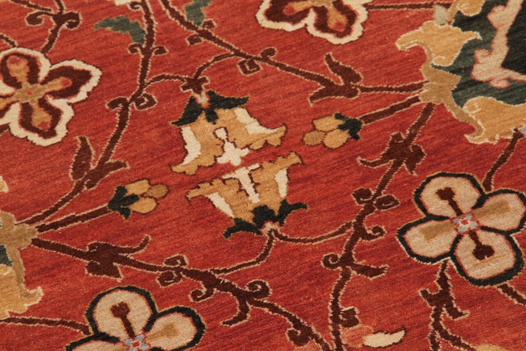 Una gran alfombra rectangular anudada a mano con un patrón tradicional floral y de medallón en rojo y negro, originaria de la India.