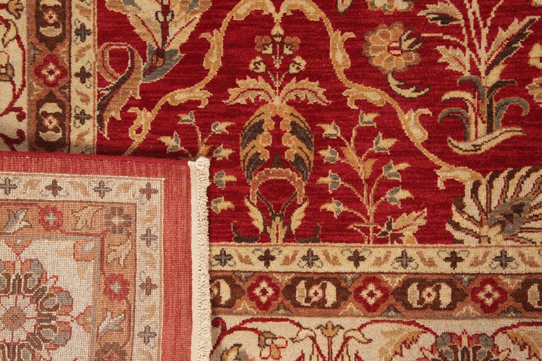 Et håndknyttet indisk tæppe med et klassisk blomsterdesign i rød og beige.