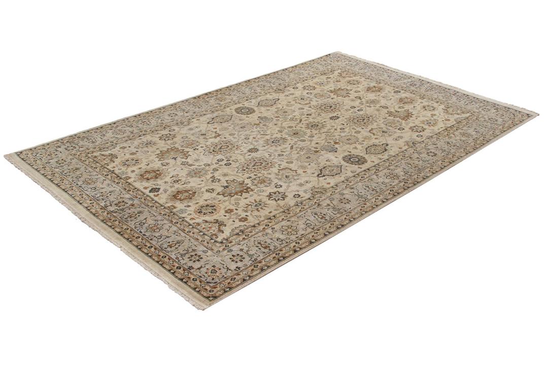 Een handgeknoopt beige tapijt uit India met een verfijnd medaillonpatroon van bloemen.