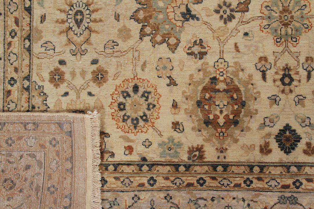 Een handgeknoopt beige tapijt uit India met een verfijnd medaillonpatroon van bloemen.
