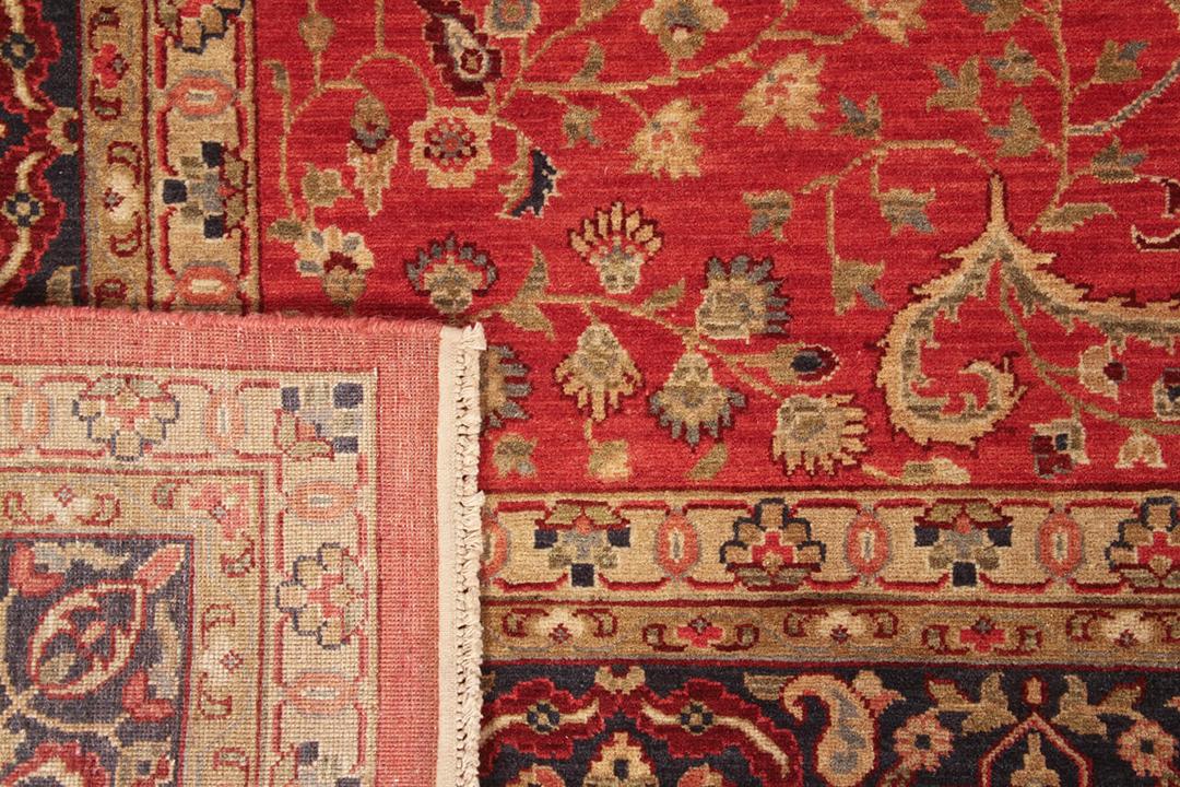 Et håndknyttet indisk tæppe med en rig rød flade og detaljerede blomstermønstre.