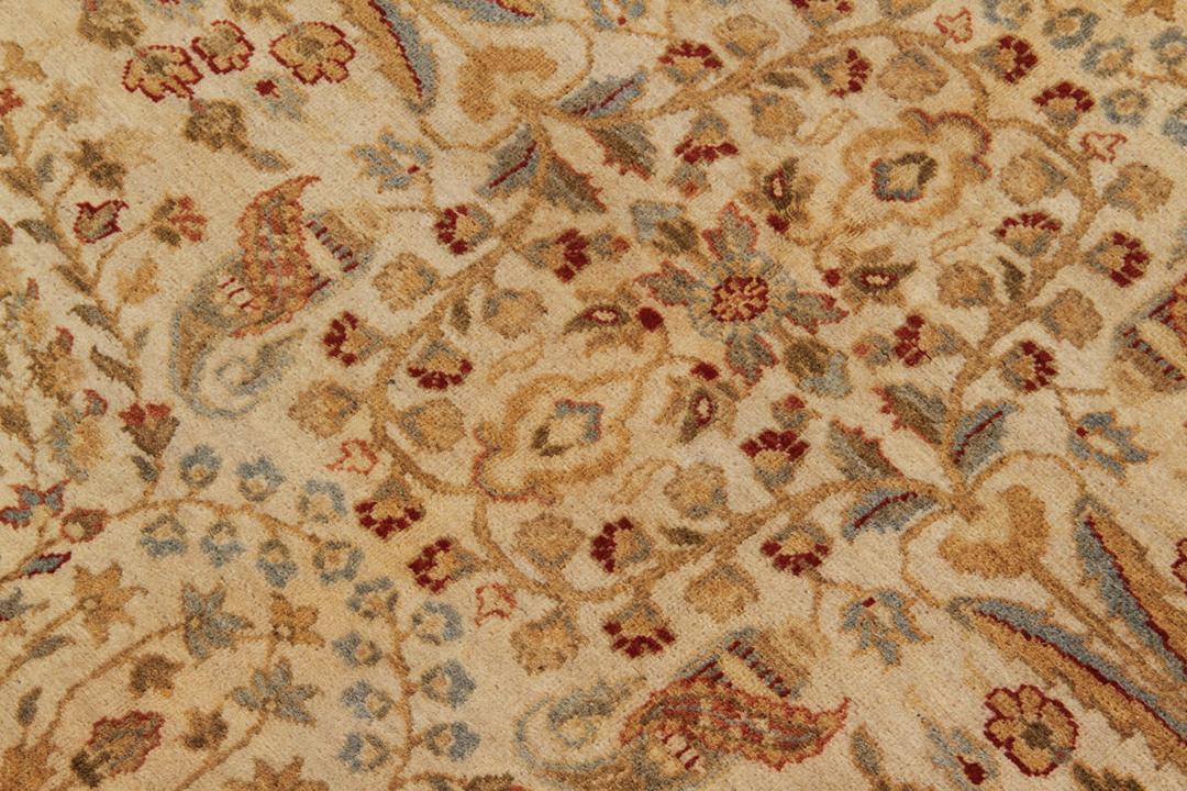 Et håndknyttet beige tæppe fra Indien med et indviklet blomstermønster.