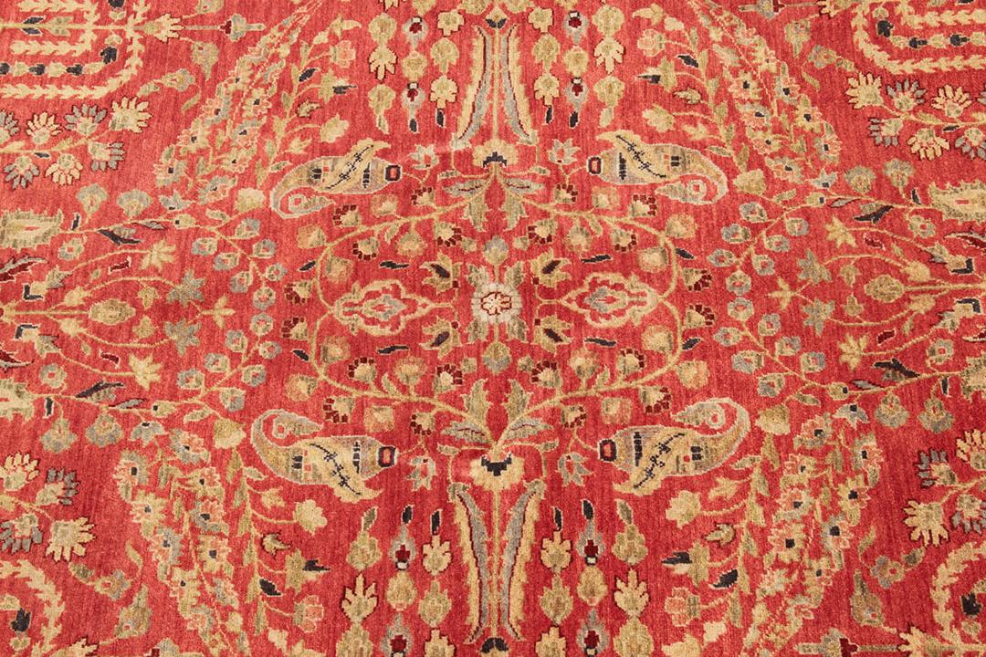 Een handgeknoopt rood Indiaas tapijt met verfijnde bloemmotieven.