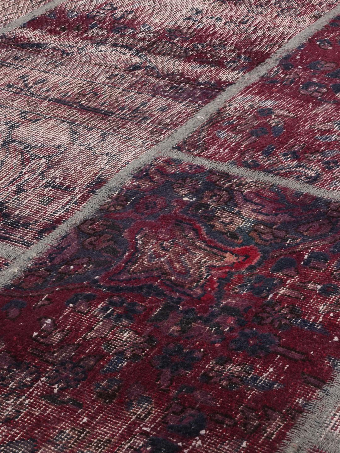A rectangular patchwork rug from the Middle East featuring a dark-red and dark-blue colour palette.