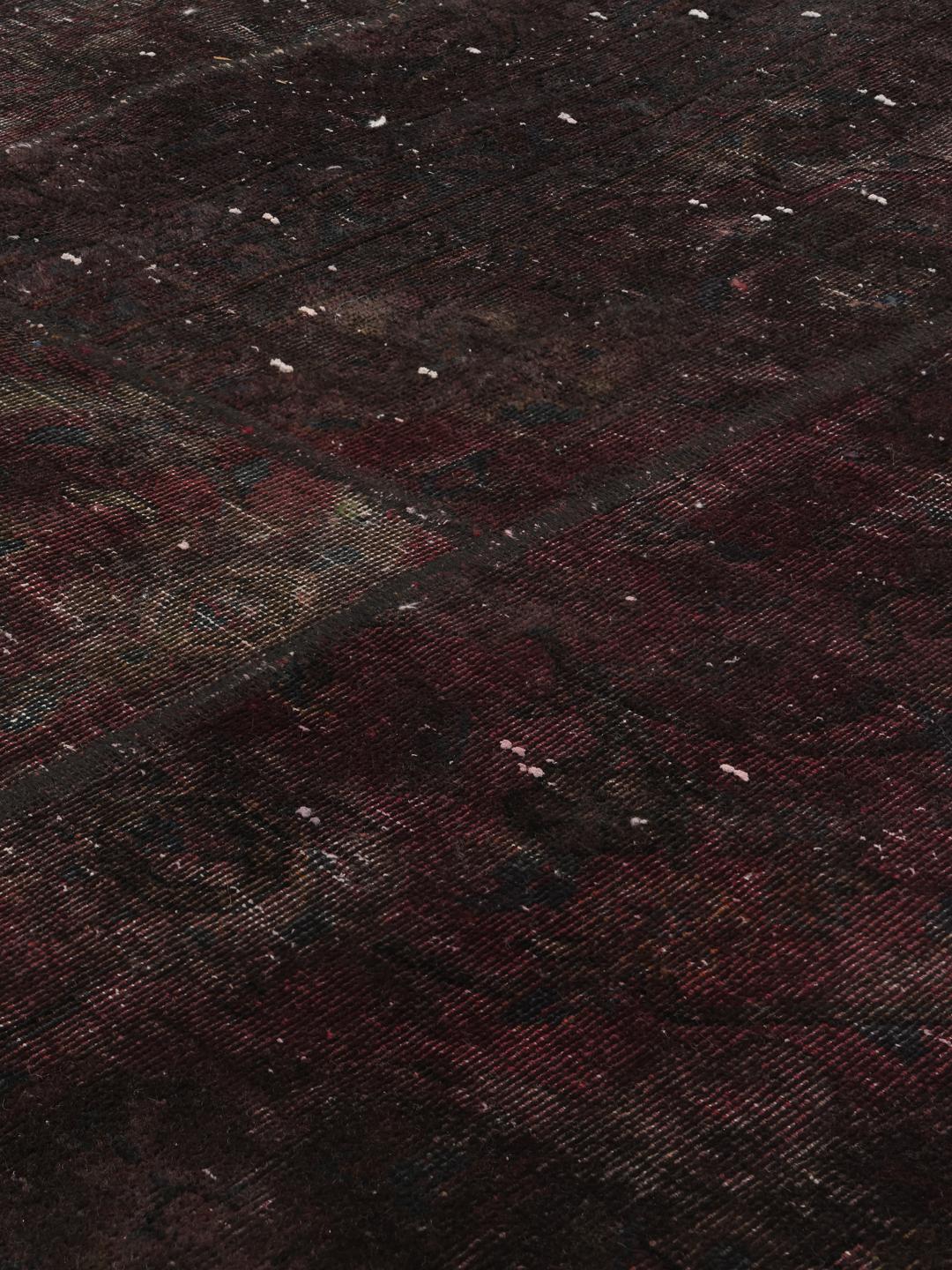 A large rectangular patchwork rug with dark-grey and dark-red tones, Middle Eastern origin.