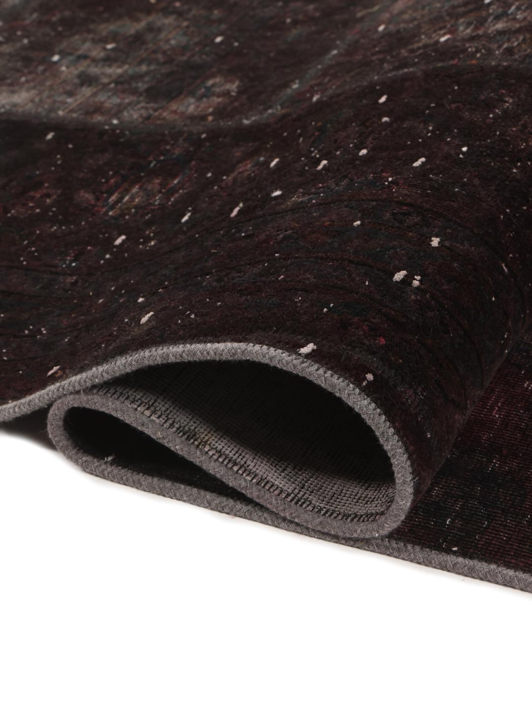 A large rectangular patchwork rug with dark-grey and dark-red tones, Middle Eastern origin.