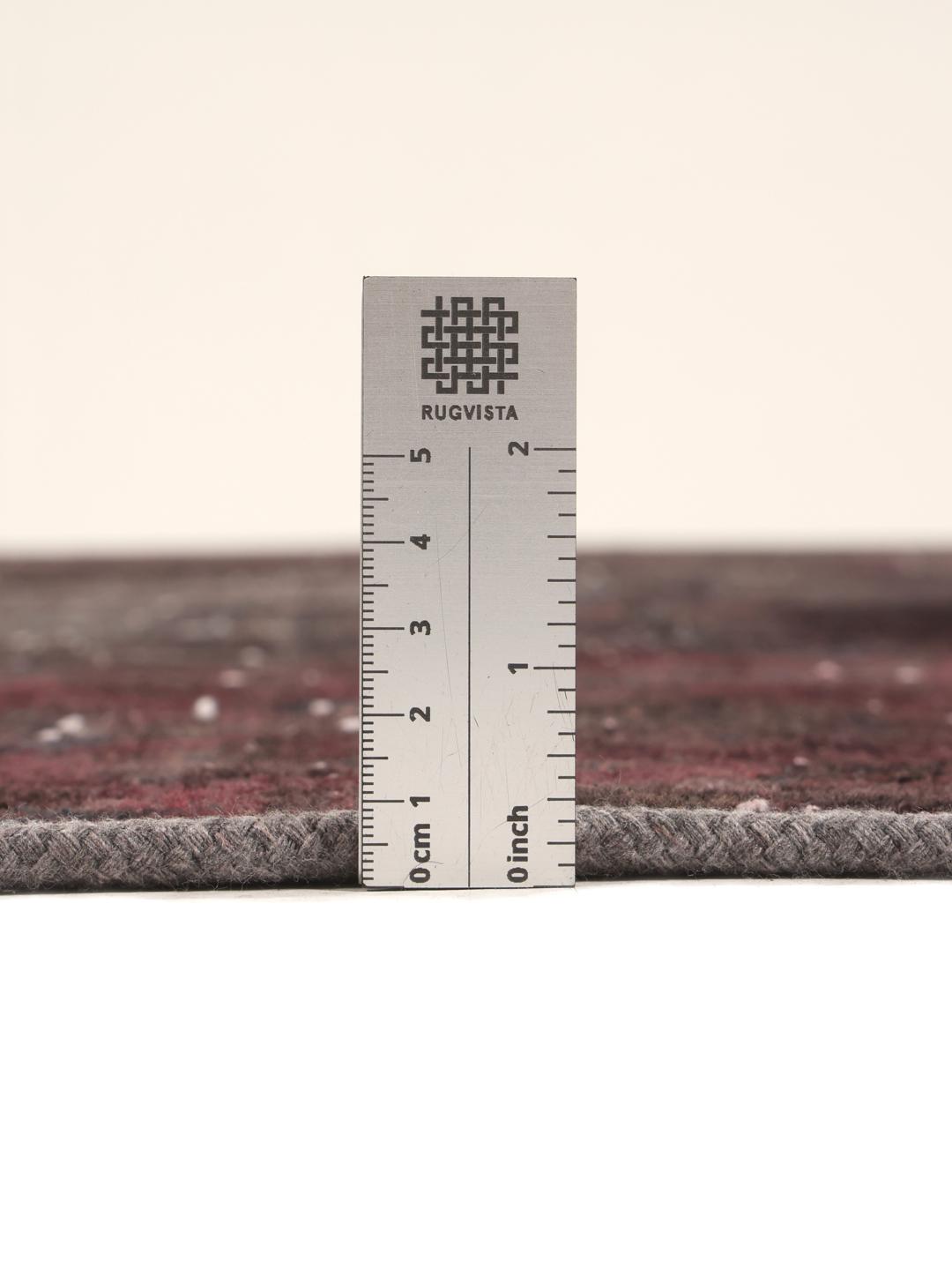 A large rectangular patchwork rug with dark-grey and dark-red tones, Middle Eastern origin.