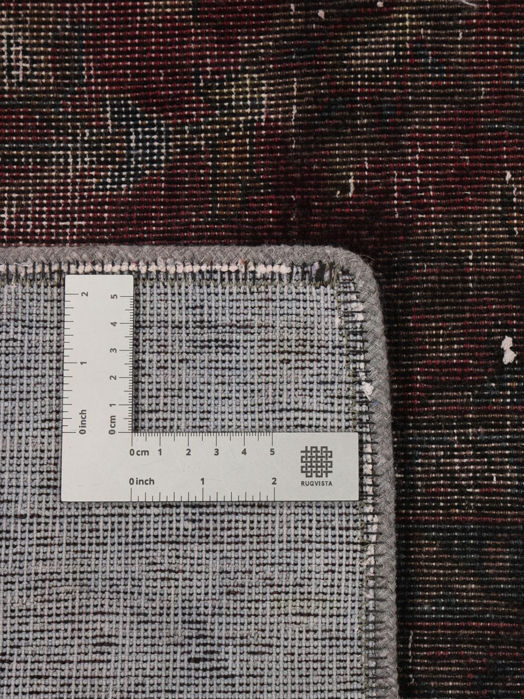 A large rectangular patchwork rug with dark-grey and dark-red tones, Middle Eastern origin.