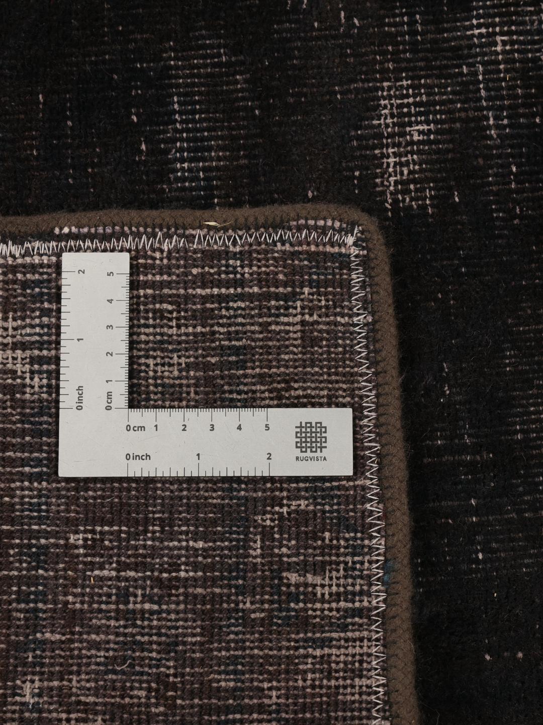 Een vierkant zwart patchwork tapijt met een textuurrijke, moderne afwerking.