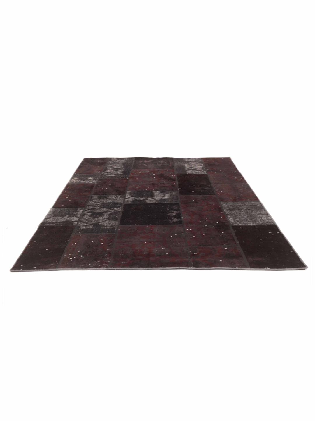 A rectangular patchwork rug from the Middle East in black and dark-grey tones.