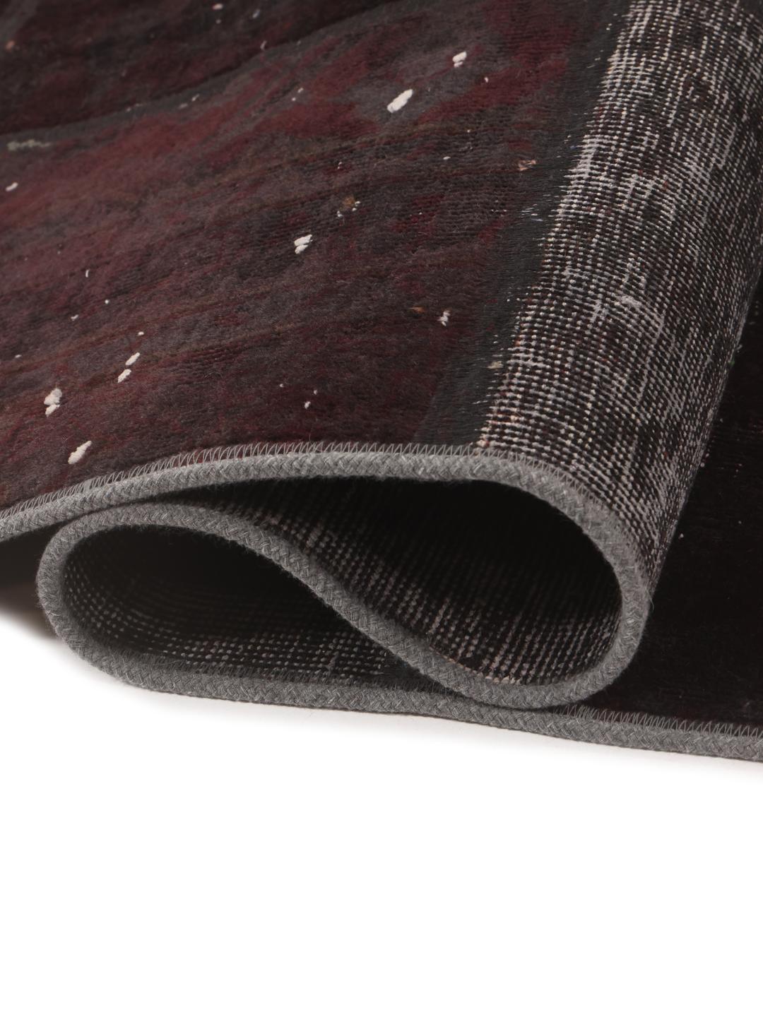 A rectangular patchwork rug from the Middle East in black and dark-grey tones.