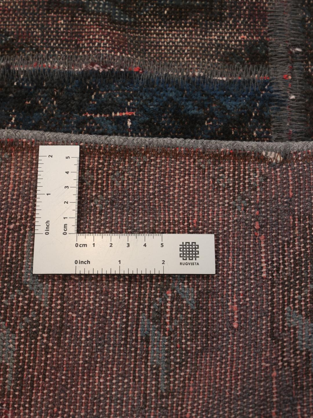 A unique patchwork rug featuring various hand-knotted fragments in deep, dark-grey and red tones.